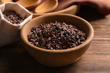 Bowl with cocoa nibs on wooden table