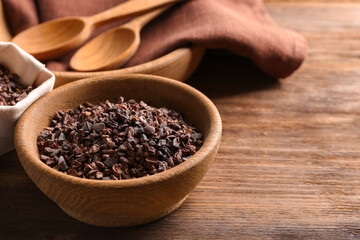 Bowl with cocoa nibs on wooden table