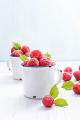 Fresh raspberries in  white ceramic mugs, with copy space. Selective focus.