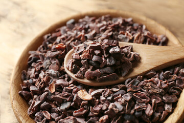 Wooden bowl and spoon with cocoa nibs, closeup