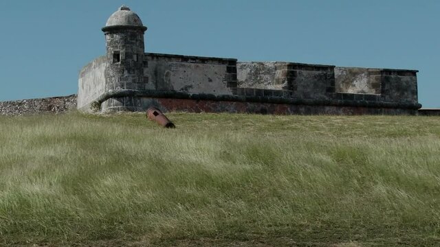 Wind blowing through grass at San Pedro de la Roca Castle near Santiago de Cuba. Old cannon living near wall and turret