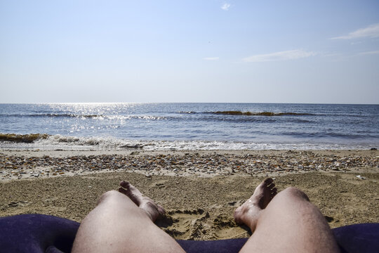 The legs of a man on a beach background. A man lies on an amatrace on the beach and is resting. Legs in the frame.