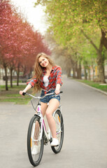 Fototapeta na wymiar Young smiling girl cycling in park