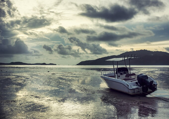 Lonely white motor boat aground in Andaman sea on sunrise