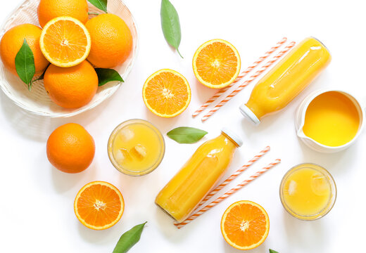 Variety of orange juice in bottles and glasses, straws, oranges isolated on white background top view.