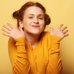 Beautiful young surprised redhair woman over yellow background