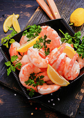 Tiger shrimps with spice and lemon on black wooden board.