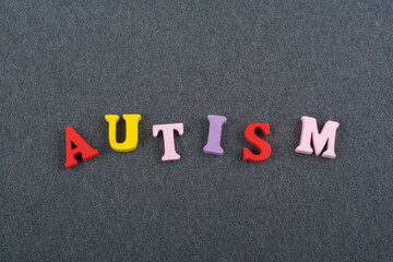 AUTISM word on black board background composed from colorful abc alphabet block wooden letters, copy space for ad text. Learning english concept.