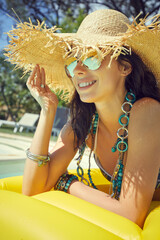 woman in bikini sunbathing on air mattress in the swimming pool