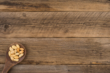 Peanuts in wooden spoon on an old wooden background.