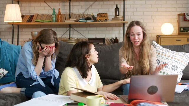 young female student becomes nervous and upset, because computer laptop breaks down and she loses everything, while studying seriously with friends together at home to prepare for difficult exam test