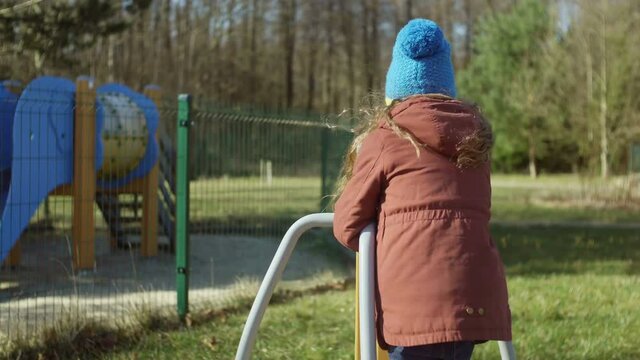 Happy little girl in good mood playing on the playground. Female turning on the carousel and smling. Carefree childhood.