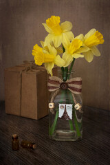 Still life with Narcissus and small bottles. Narcissus in a bottle on a wooden table.