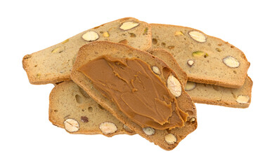 Several slices of almond pistachio crisp bread slices with cookie butter spread on one slice isolated on a white background.