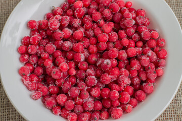 Frozen cranberries in a white plate on a piece of burlap
