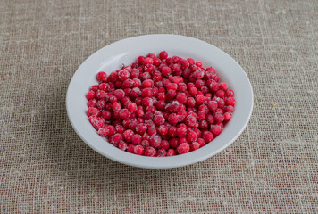 Frozen cranberries in a white plate on a piece of burlap