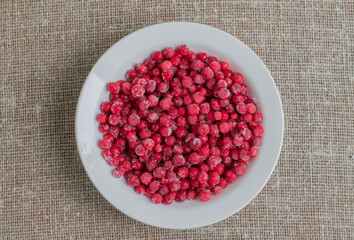 Frozen cranberries in a white plate on a piece of burlap
