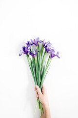 Female hand holding beautiful purple iris flowers bouquet on white background. Flat lay, top view.