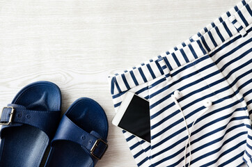 Shorts, slippers and phone on wooden table on summer