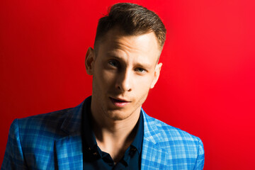 Portrait of young confident man dressed in tuxedo on red background