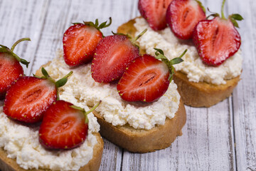 Sandwich of strawberry and cottage cheese on the wooden table, close up