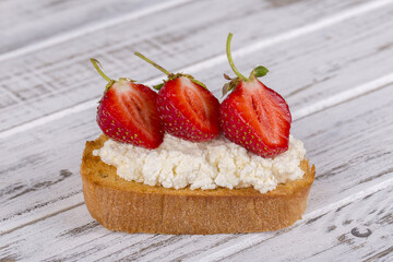 Sandwich of strawberry and cottage cheese on the wooden table, close up