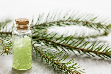 Obraz na płótnie Canvas Bottles of sea salt and fir branches for aromatherapy and spa on white table background