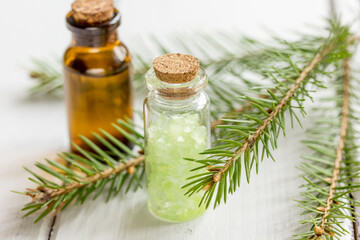 Bottles of essential oil and fir branches for aromatherapy and spa on white table background
