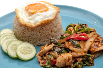 Chicken stir fried with chili paste and some vegetable, served with fried egg, rice and cucumber on the plate