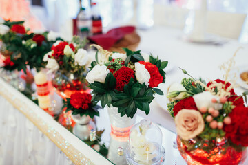 Red bouquets with greenery stand on mirror trays