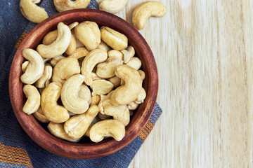 Cashew nuts in wooden bowl. Top view with copy space