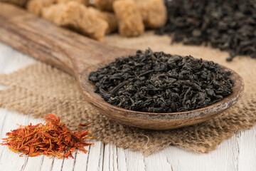 Black tea in a wooden spoon and an old white table.