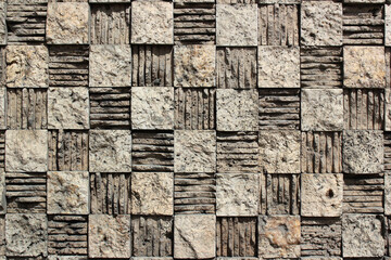 Textured checkered background of relief stone mosaic on a wall