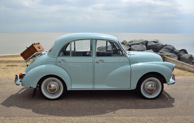 Classic Light Blue Morris Minor with picnic basket parked on seafront promenade.