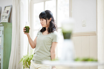 グリーンスムージーを持つ女性 