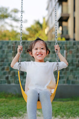Happy cute little girl on swing in the park.
