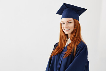Happy redhead female graduate smiling over white background. Copy space.