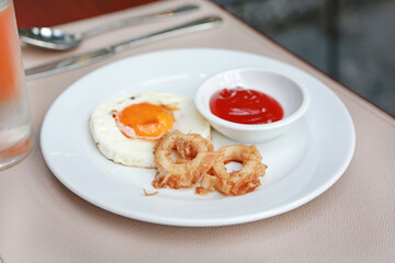 fried calamari rings and fried egg with tomato sauce on plate.