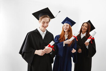Happy international graduates smiling rejoicing holding diplomas over white background.