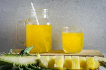 Pineapple juice in a jar and glass on stone table.