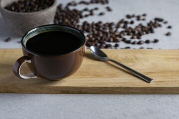 Brown cup of coffee with coffee bean on a stone table.