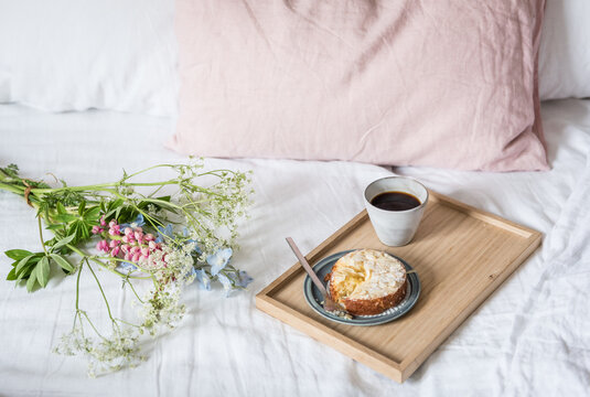 Fr&uuml;hst&uuml;ck im Bett mit s&uuml;&szlig;em Kuchen und Kaffee mit Blumen