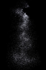 Sifting white caster sugar over black background. Isolated