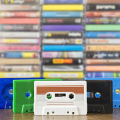 Stack of old colorful dirty audio cassettes and cases on the brown wooden shelf