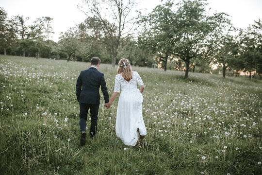 bride and groom walking on field from behind
