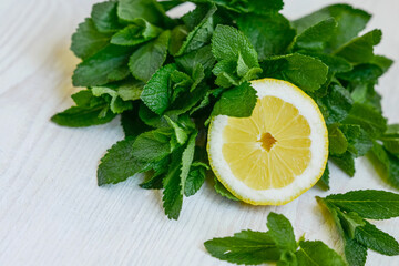Fresh juicy mint leaves and lemon on a white wooden background