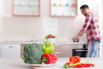 Fresh vegetables on table with man cooking in background