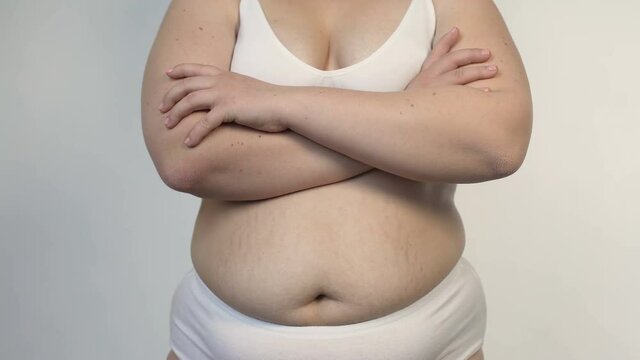 Body shaming, overweight female in white lingerie posing with folded hands