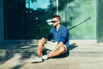 Sitting handsome man in blue shirt and stylish shorts