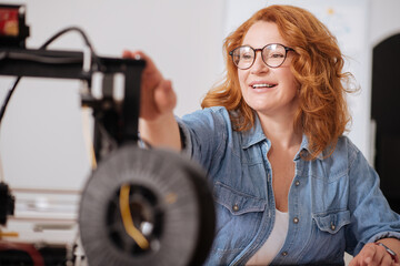 Positive joyful woman looking at the 3D printer